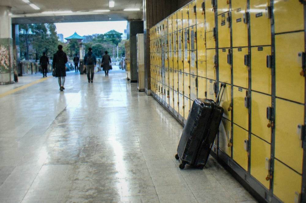 A station concourse with rows of yellow coin lockers beside a wide corridor