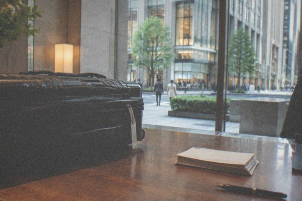 A packed suitcase being handed over at a hotel concierge counter for courier forwarding