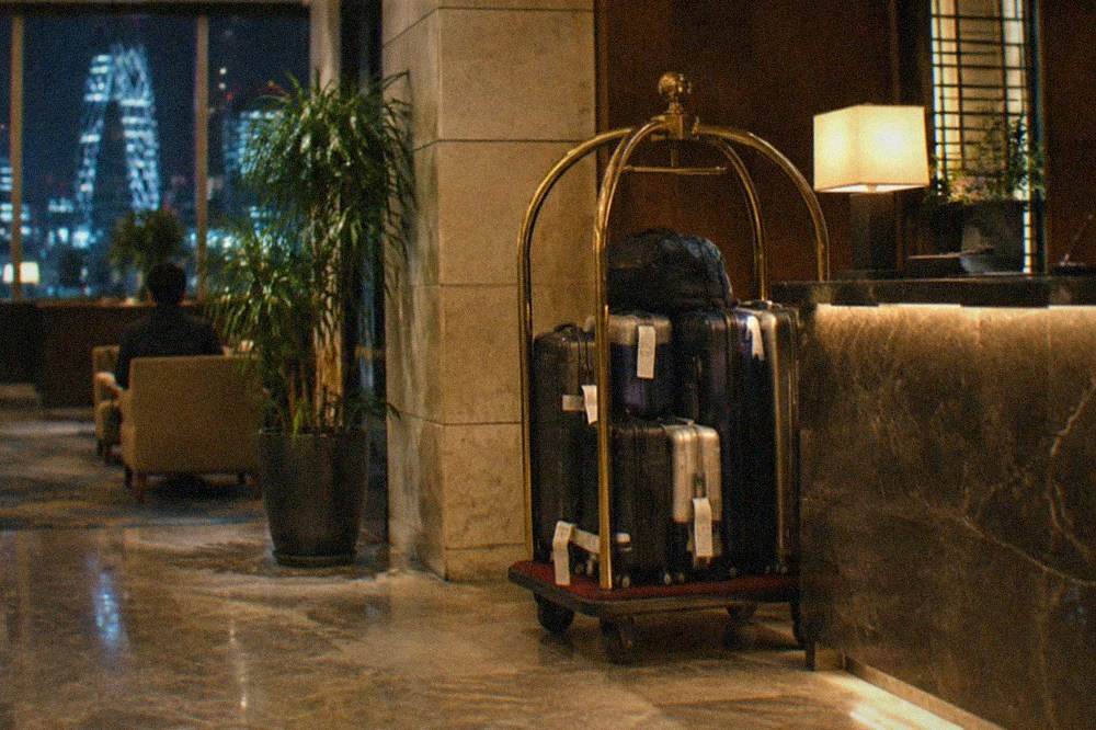 A hotel lobby luggage trolley with tagged suitcases lined up behind the front desk