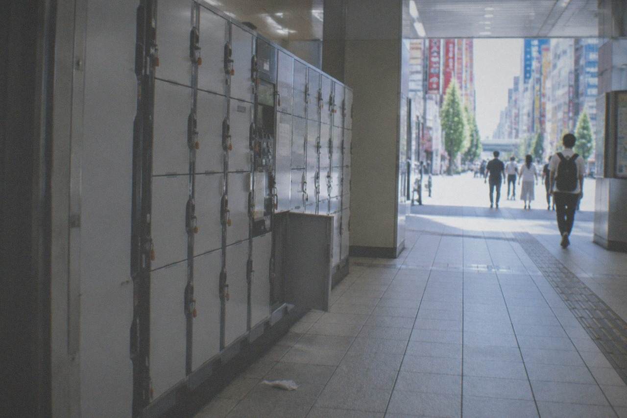 A bank of coin lockers in different sizes along a bright Tokyo station corridor