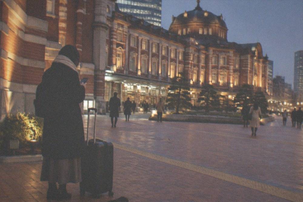 A traveller checking a forwarding deadline on a phone beside a packed suitcase