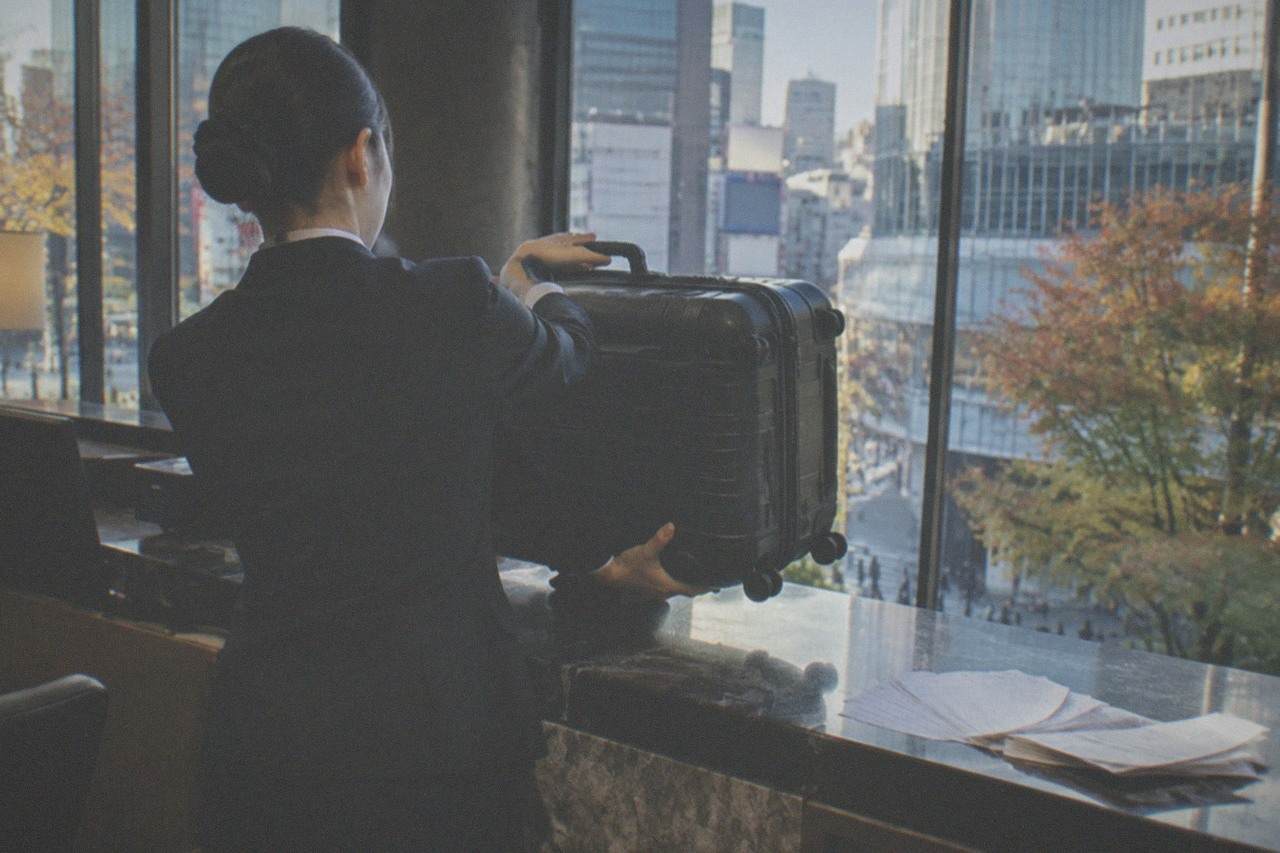 A hotel front desk clerk accepting a suitcase for forwarding to an airport