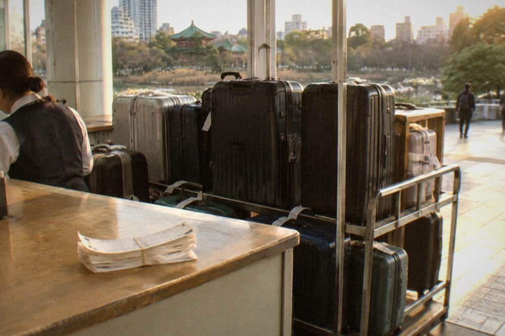 A staffed luggage storage counter with suitcases lined up behind the desk in a Tokyo station