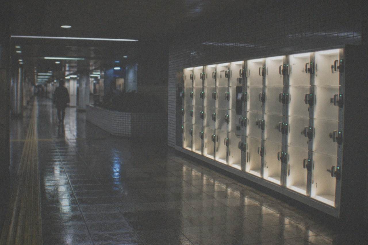 A quiet Tokyo station corridor at night with a row of illuminated coin lockers along the wall.