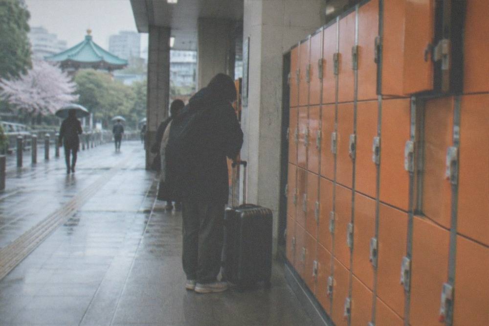 Rows of orange coin lockers along a station corridor with a suitcase in front of them