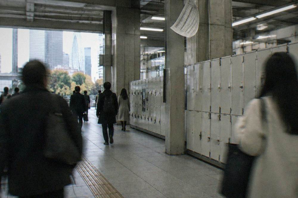 Shinjuku Station west exit concourse with commuters passing a row of lockers
