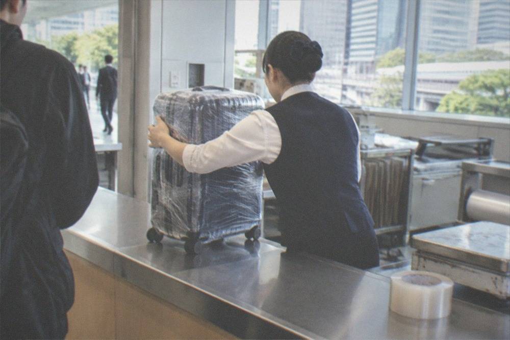 A wrapped suitcase being handed over at a luggage forwarding counter in Tokyo
