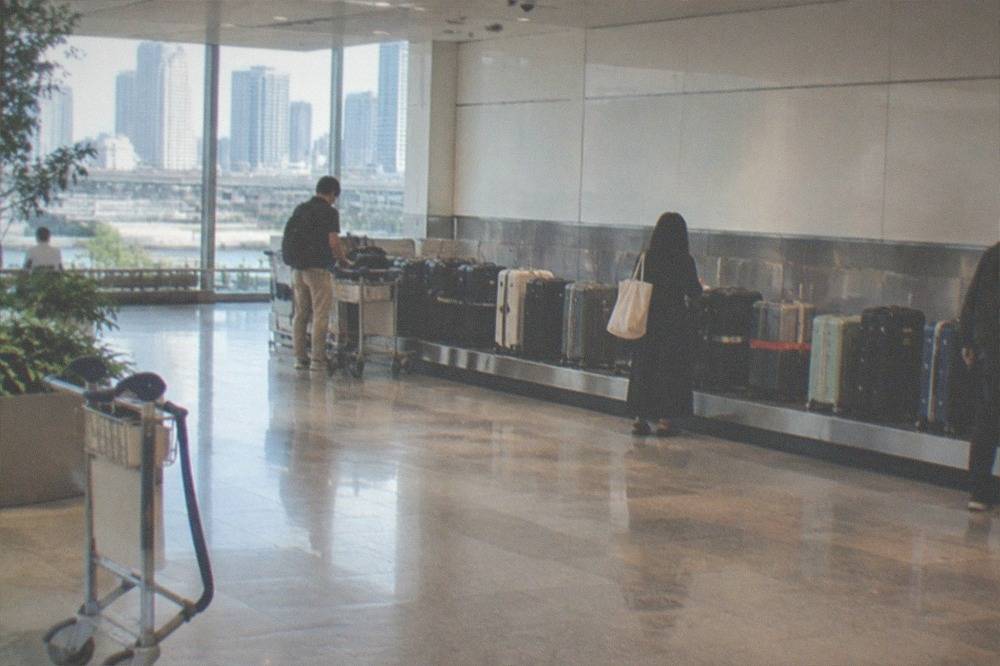 An attended airport baggage storage counter with large suitcases lined up beside it