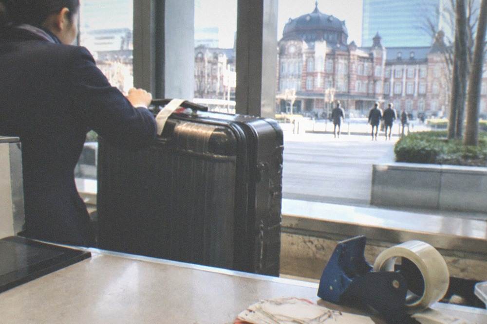 A large suitcase being checked in at a luggage forwarding counter in Tokyo