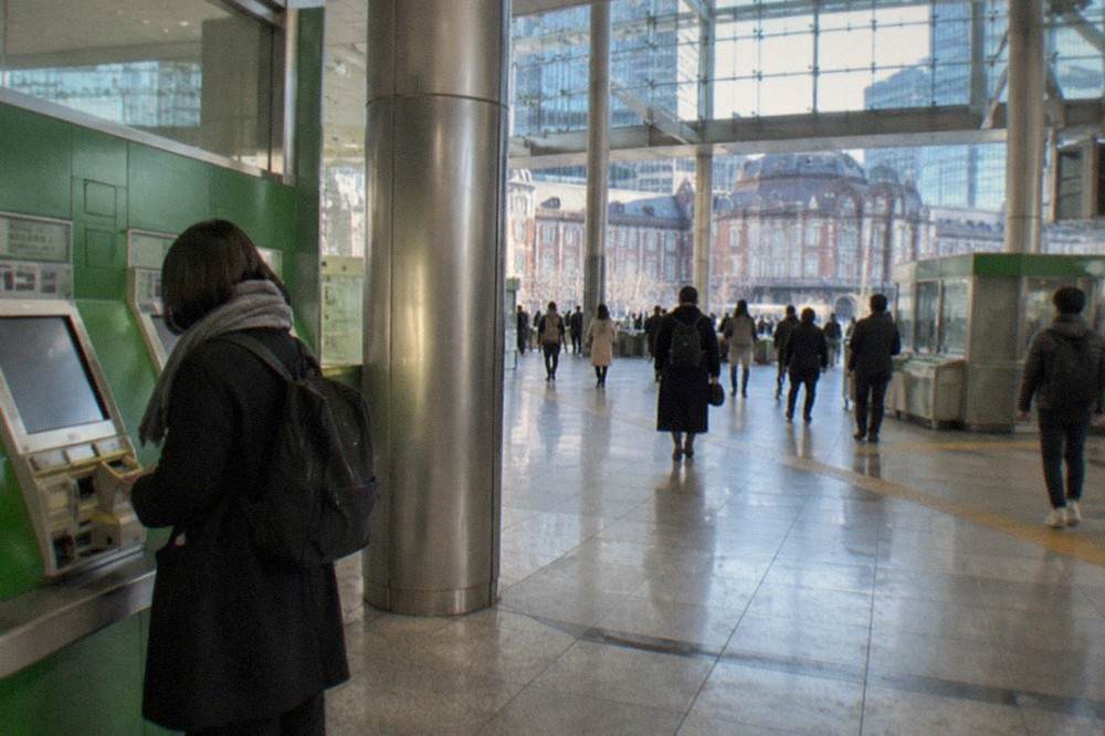 Shinkansen ticket machines and a green ticket window in a bright station concourse