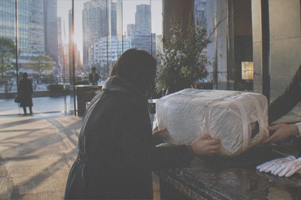 A wrapped suitcase being handed over at a hotel front desk for courier forwarding
