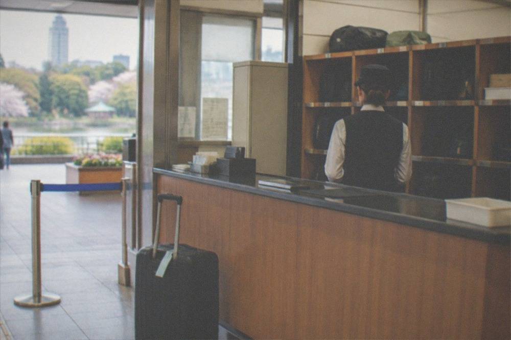 A staffed baggage counter inside a train station with numbered shelves behind the attendant