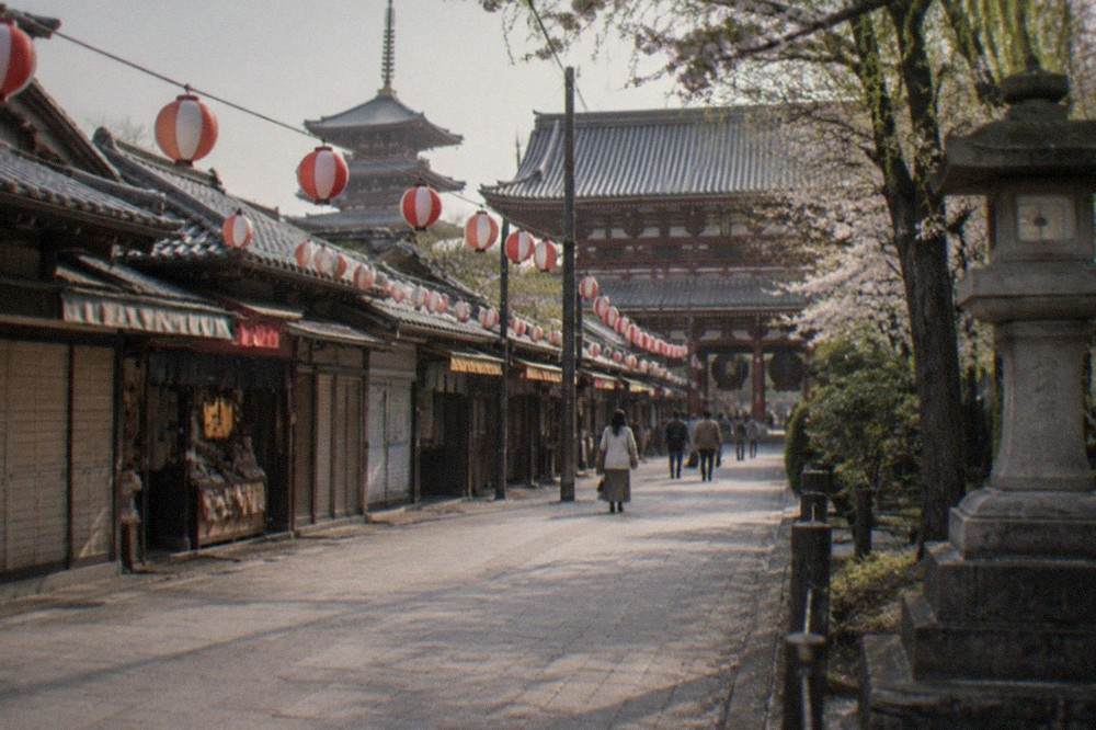 A temple quarter street with paper lanterns strung across the pavement in daylight