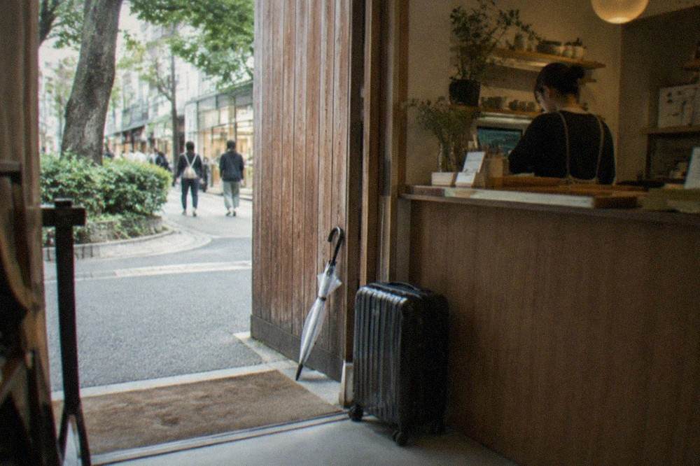 Suitcase parked beside a shop counter in a Tokyo storefront, no people.